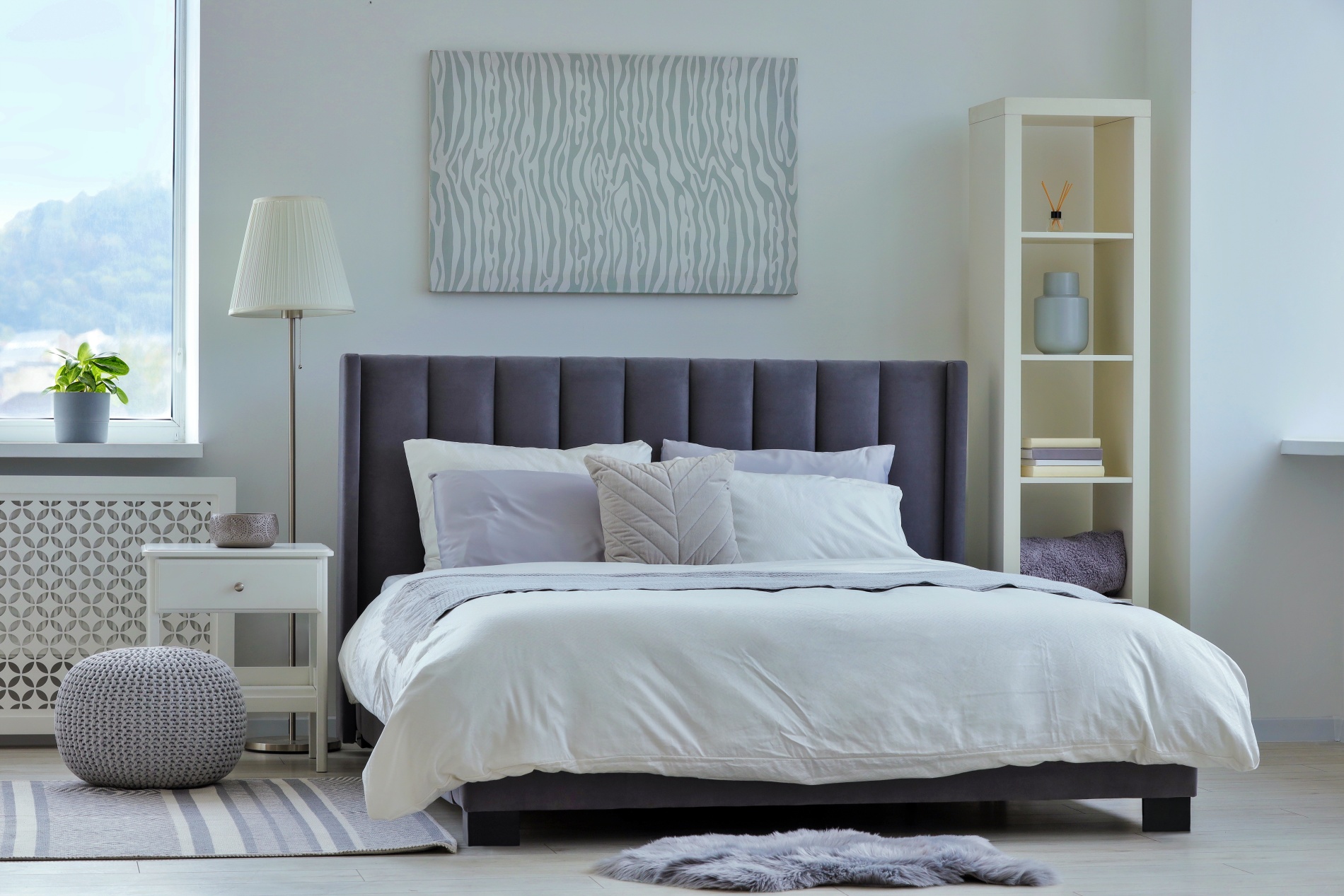 Stylish light bedroom interior with large comfortable bed.