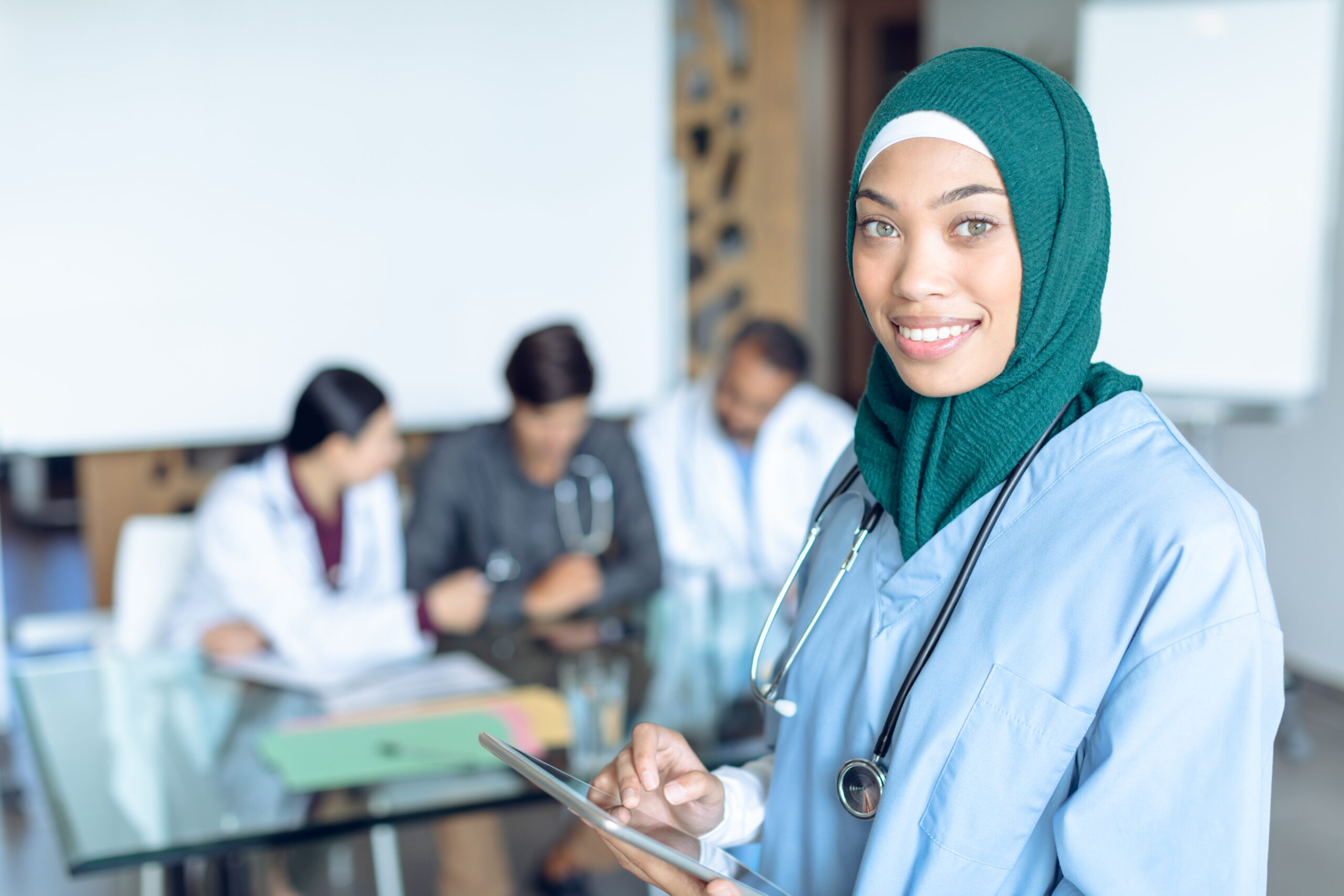 Female Muslim medical professional holding a digital tablet.