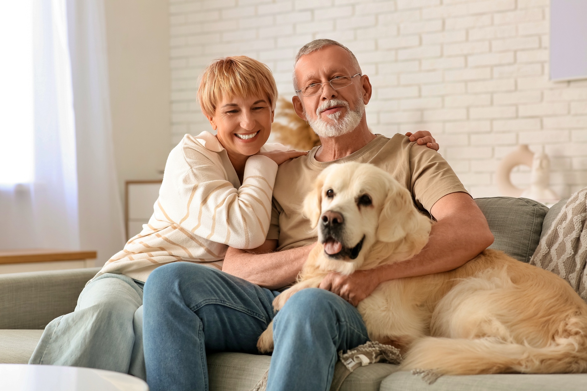 Mature couple, husband and wife, sitting on the couch with the pet dog.