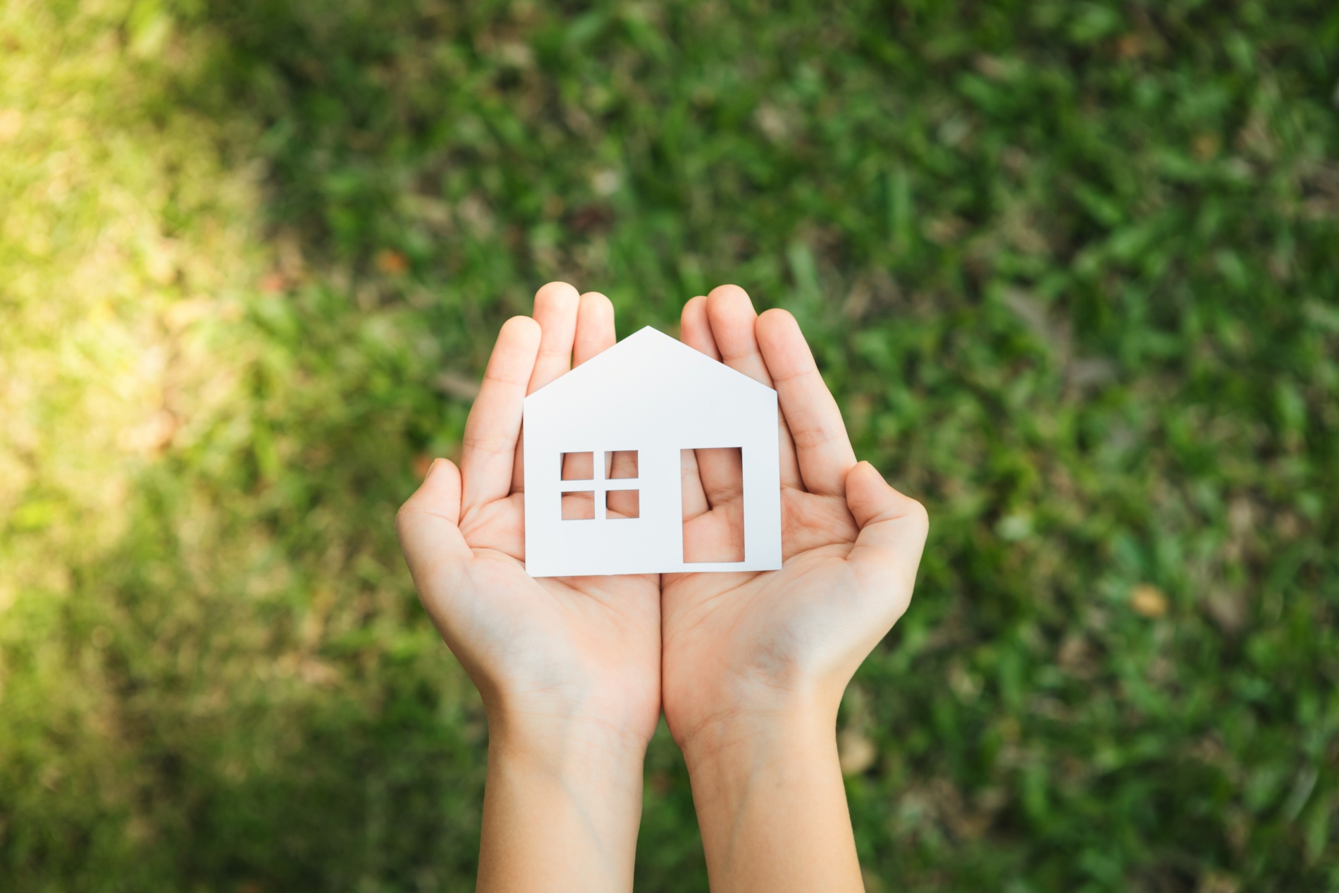 Hands open holding an icon of a house in their hands