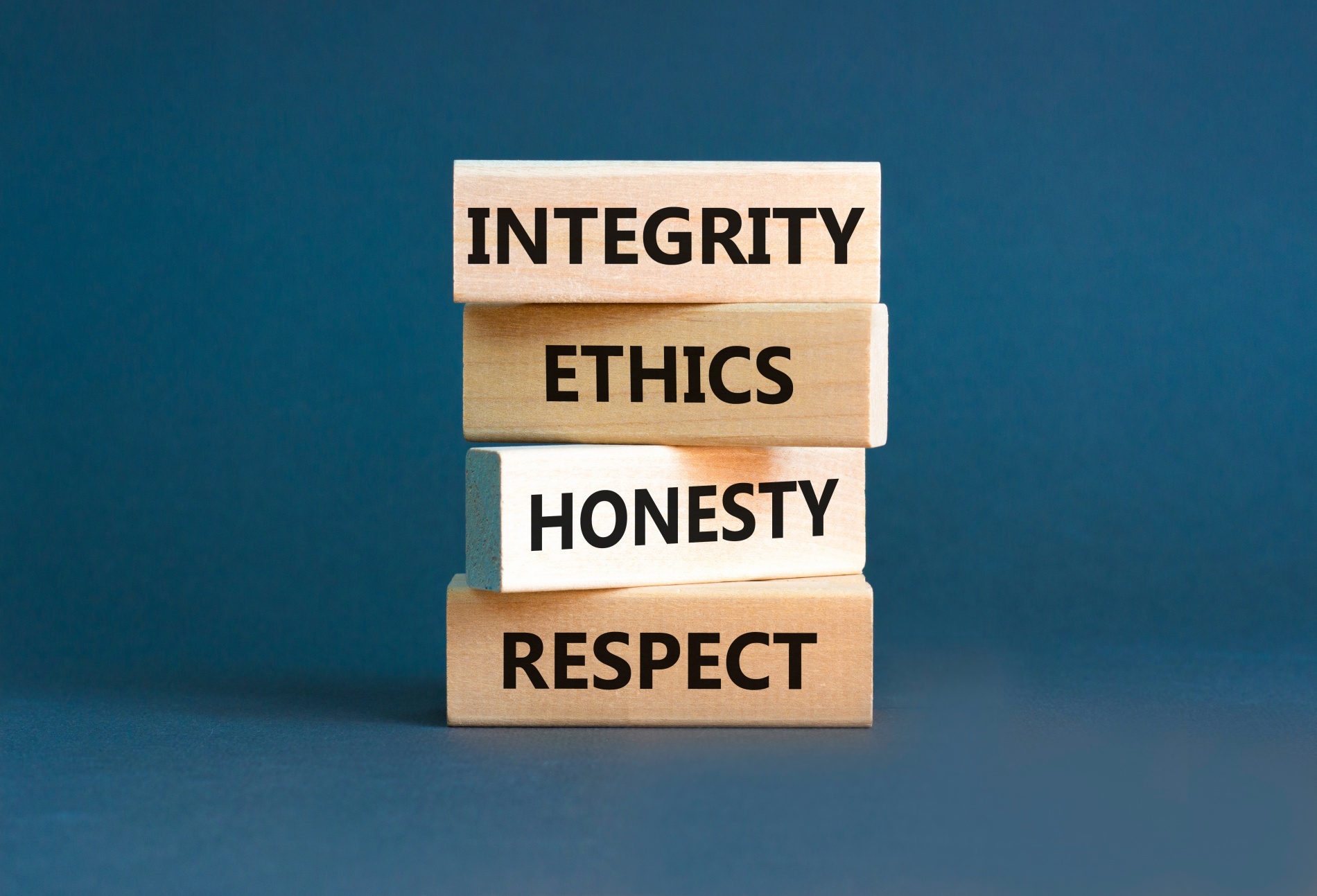 Wooden blocks stacked on each other each block saying, integrity, ethics, honesty, respect.