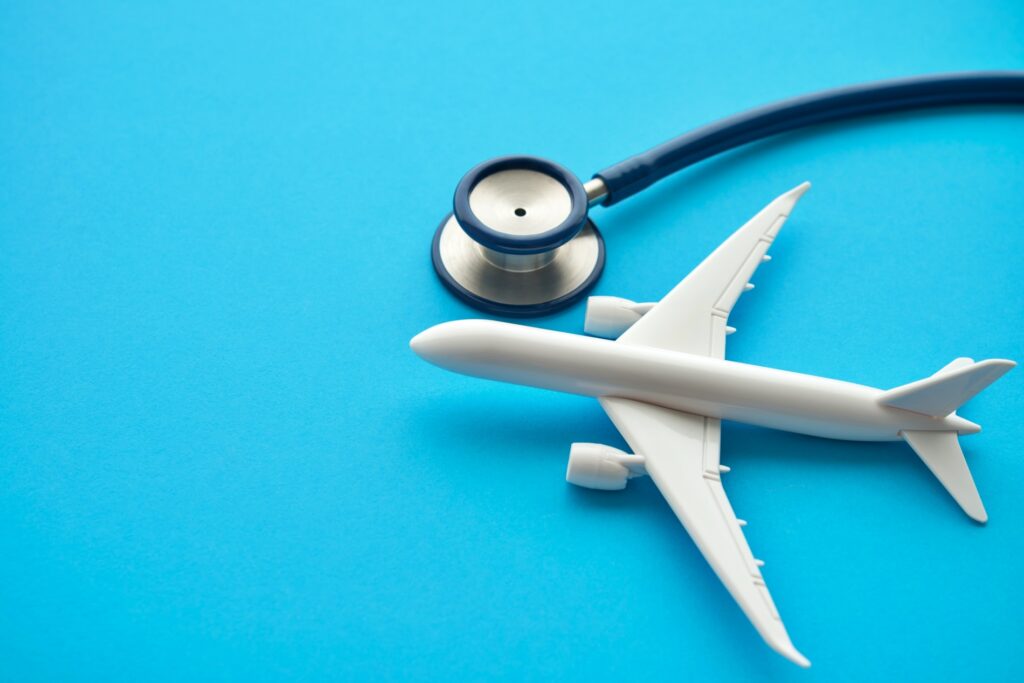 Airplane and stethoscope on blue background.